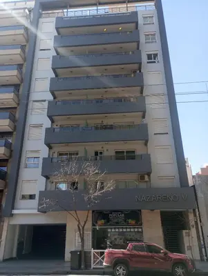 a red car parked in front of a building at Departamento un dormitorio Frente al Pocito in Cordoba