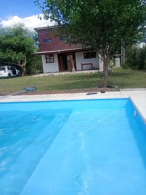 a large blue swimming pool in front of a house at Cabaña Mitimay in Alta Gracia
