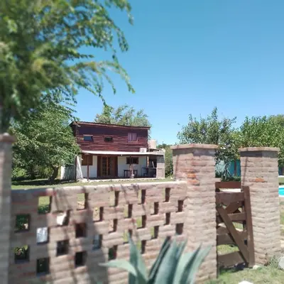 a house behind a brick wall with a fence at Cabaña Mitimay in Alta Gracia