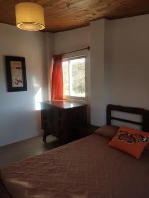a bedroom with a bed and a dresser and a window at La Pasionaria, casa de campo con pileta in Villa García