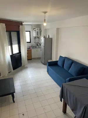 a living room with a blue couch and a kitchen at DEPARTAMENTO 1 dormitorio plaza Colón en la mejor zona del centro de Córdoba in Cordoba