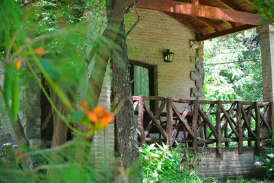 a brick house with a wooden porch and a tree at Las Nubes Cabañas & Loft in San Javier