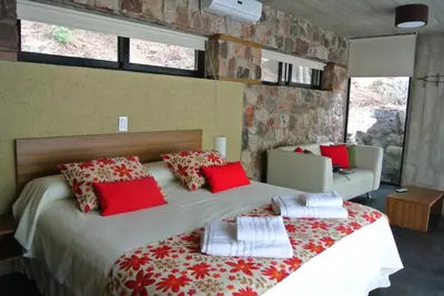 a bedroom with a large bed with red and white pillows at Las Nubes Cabañas & Loft in San Javier