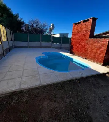 a swimming pool in a yard next to a brick wall at Casita serrana in Villa Santa Cruz del Lago