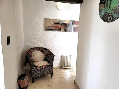 a chair in a room with a clock on the wall at Mujer Urbana Suite in Cordoba