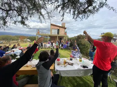 a group of people standing around a table with their arms in the air at Cabañas Y Departamentos Bettylu in Villa Cura Brochero
