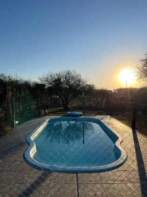 a small swimming pool with the sun setting in the background at ALPINAS DeL MONTE in Cortaderas