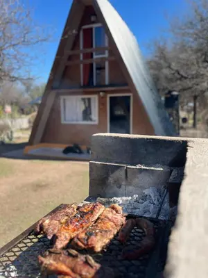 a grill with meat and sausages on it in front of a house at ALPINAS DeL MONTE in Cortaderas