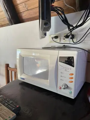 a white microwave sitting on top of a table at Cabañas Pindahue - Alojamineto Epehuen in Villa Carlos Paz