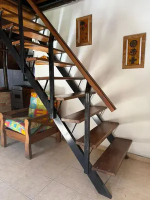 a wooden staircase next to a wall with a bench at Cabañas Pindahue - Alojamineto Epehuen in Villa Carlos Paz