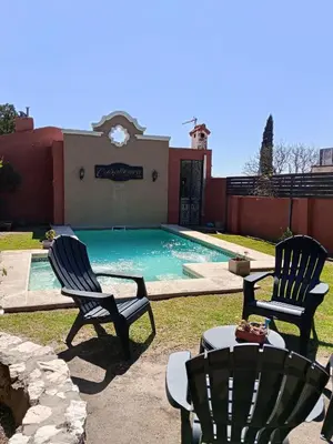 two chairs sitting next to a swimming pool at La caballeriza departamentos in Alta Gracia