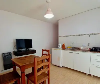 a kitchen with a wooden table and a kitchen with a tv at La caballeriza departamentos in Alta Gracia