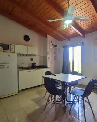 a kitchen with a table and chairs and a ceiling fan at La caballeriza departamentos in Alta Gracia
