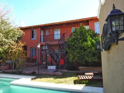 a red building with a staircase next to a pool at La caballeriza departamentos in Alta Gracia