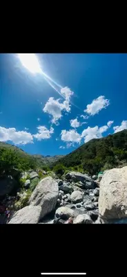 a sun shining over a river with rocks and trees at Alojamiento Mabel in Merlo