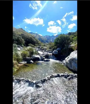 a stream of water with rocks and mountains in the background at Alojamiento Mabel in Merlo