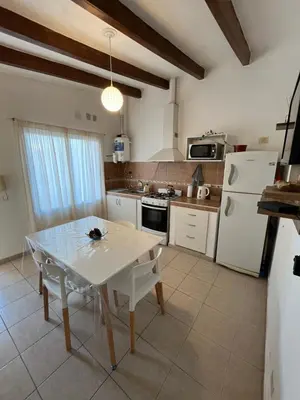 a kitchen with a table and a white refrigerator at Melodía del lago in Villa Carlos Paz
