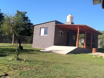 a small house in a yard with a grass field at Punilla- Don Americo in Villa Carlos Paz