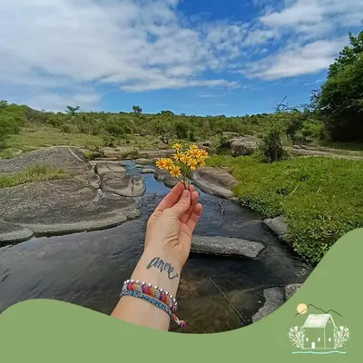 a person holding a flower in front of a river at Punilla- Don Americo in Villa Carlos Paz