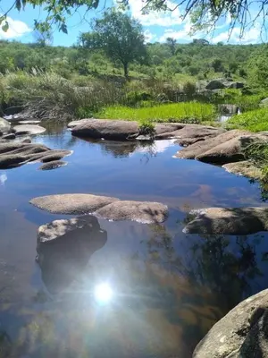 a river with rocks and the sun in the water at Punilla- Don Americo in Villa Carlos Paz