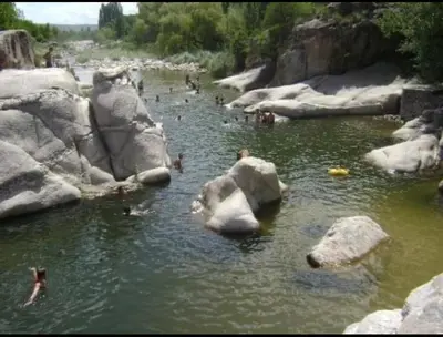 a group of people swimming in a river with rocks at La Herminda Casas de Campo in Nono