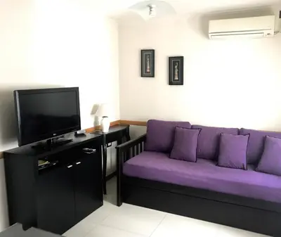 a living room with a purple couch and a tv at DPto Carlos Paz in Villa Carlos Paz