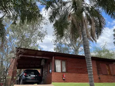 a car parked in front of a house with a palm tree at Cabañas Antílope & Spa in Tanti