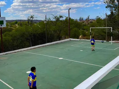 two young boys playing tennis on a tennis court at Cabañas Antílope & Spa in Tanti