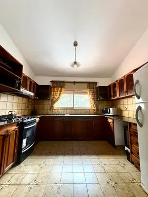 a large kitchen with wooden cabinets and a window at El Nogal in Villa Carlos Paz