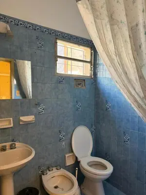 a blue tiled bathroom with a toilet and a sink at El Nogal in Villa Carlos Paz