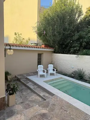 a patio with two white chairs and a swimming pool at El Nogal in Villa Carlos Paz
