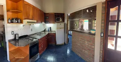 a kitchen with wooden cabinets and a brick wall at El refugio in Villa del Dique