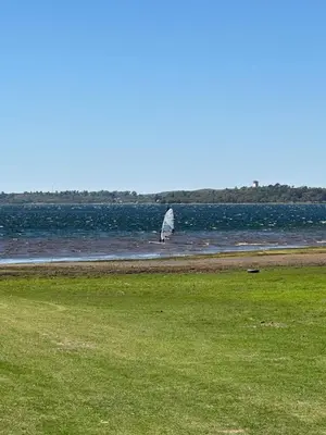 a sail boat in the water with a grass field at El refugio in Villa del Dique