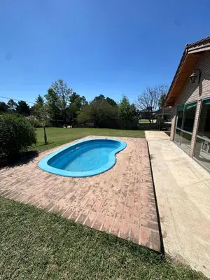 a swimming pool in the grass next to a house at El refugio in Villa del Dique