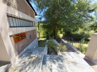 a building with a bench next to a tree at La Morada del Arroyo in Villa Parque Siquiman
