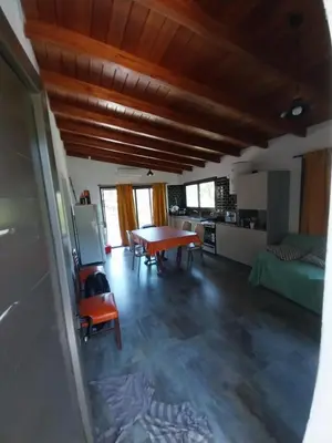 a living room with a table and a kitchen at La Morada del Arroyo in Villa Parque Siquiman