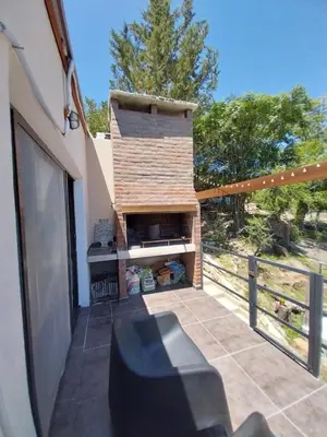 a patio with a brick fireplace next to a fence at La Morada del Arroyo in Villa Parque Siquiman