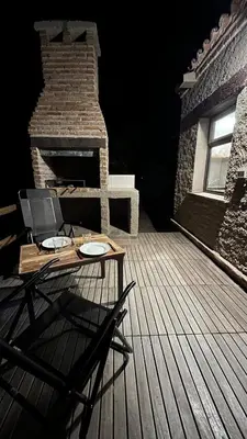 a wooden table on a deck with a brick fireplace at Terrazas Suite in Potrero de Garay