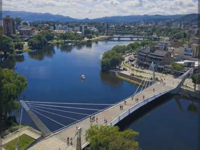 a bridge over a river with people walking on it at Monoambiente Villa Carlos Paz Centro, Terminal in Cordoba
