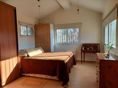 a bedroom with a bed and a dresser and two windows at Casa en Villa General Belgrano in Villa General Belgrano