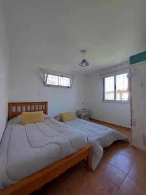 a large bed in a bedroom with two windows at Casa en Villa General Belgrano in Villa General Belgrano