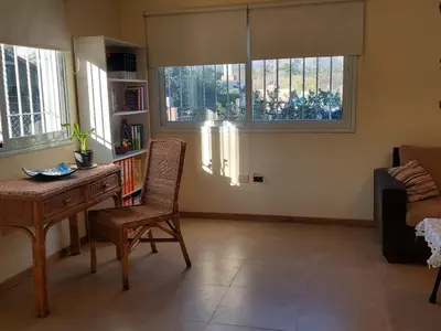 a living room with a desk and a chair and windows at Casa en Villa General Belgrano in Villa General Belgrano