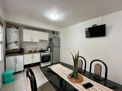 a kitchen with a dining table and a kitchen with white cabinets at Departamanto 1 dormitorio Carlos Paz Tupungato in Villa Carlos Paz