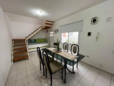 a dining room with a table and chairs and a staircase at Departamanto 1 dormitorio Carlos Paz Tupungato in Villa Carlos Paz