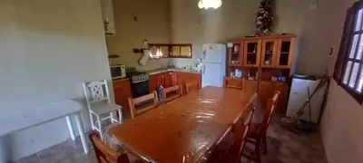 a kitchen with a wooden table with chairs and a refrigerator at Cabaña Cerca del rio Cabalango in Cavalango