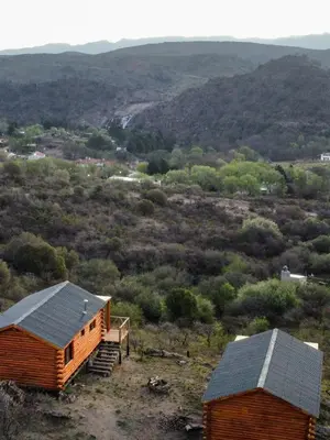 a log cabin and a house on a hill at Piedras Blancas in La Bajada