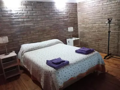 a bedroom with two beds and a brick wall at El Cardal II in Río Cuarto