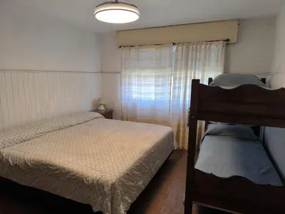 a small bedroom with two beds and a window at Casa Milu in Mina Clavero
