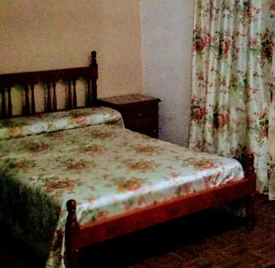 an old bedroom with a bed with a floral curtain at Casa Milu in Mina Clavero