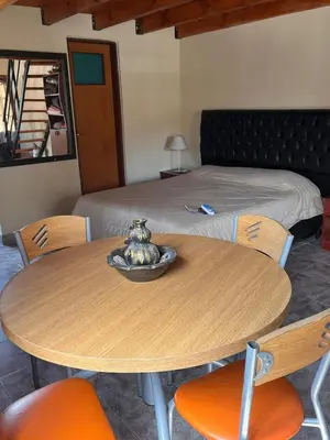 a wooden table with chairs and a bed at Un escape mágico en el centro de la ciudad in Villa General Belgrano